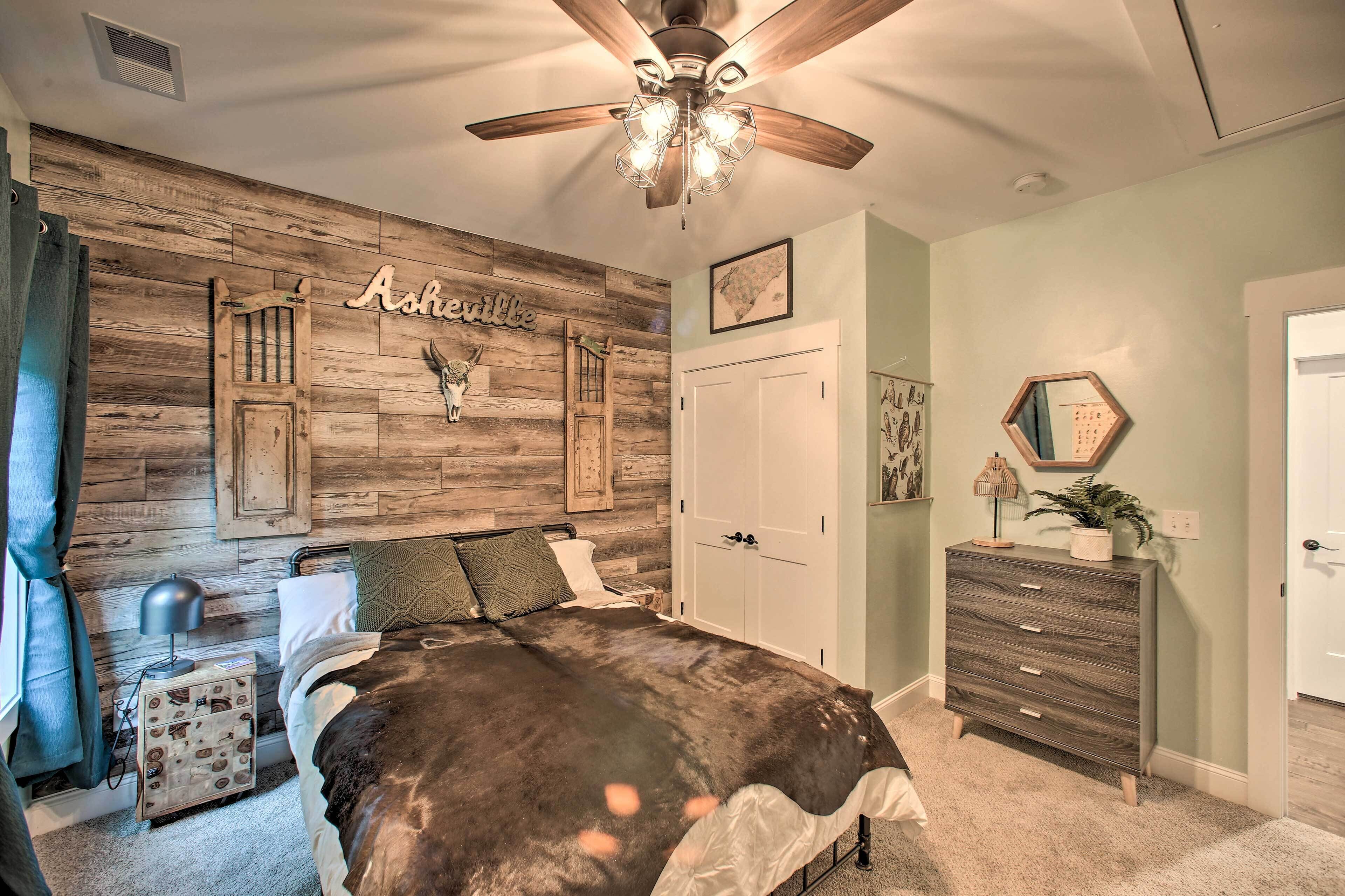A bedroom with a wooden wall, a bed, a dresser, and a ceiling fan.