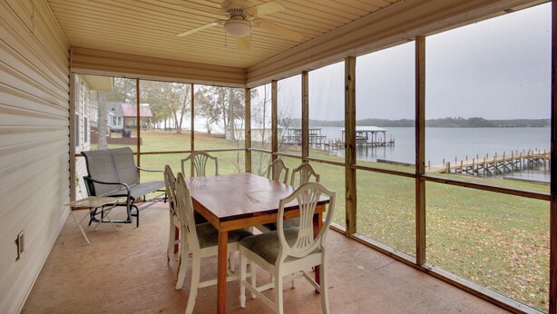 A covered patio with a wooden table and white chairs, overlooking a lake with a dock. - Lakefront House w/ Boat Ramp, Dock & Sunset Views! (Cross Hill)