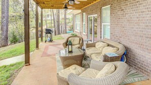 A covered patio with wicker furniture, a grill, and a view of the surrounding trees and yard. - Lakefront Leesville Retreat w/ Private Dock! (Leesville)