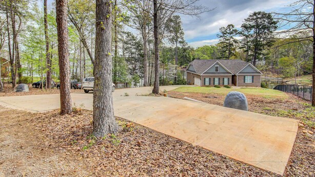 A residential property with a large driveway, a house with a gabled roof, and a wooded area. - Lakefront Leesville Retreat w/ Private Dock! (Leesville)