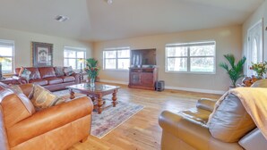 A spacious living room with a brown leather sofa, a wooden coffee table, and a television on a cabinet.