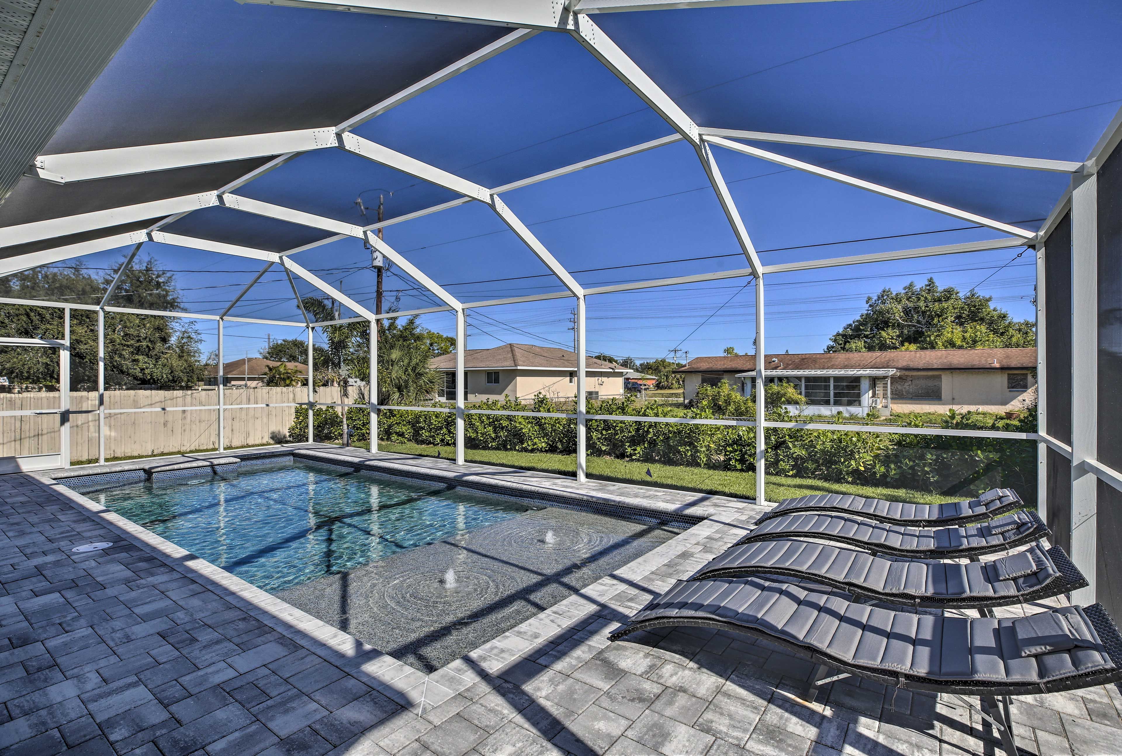 A covered outdoor swimming pool with lounge chairs and a brick patio.