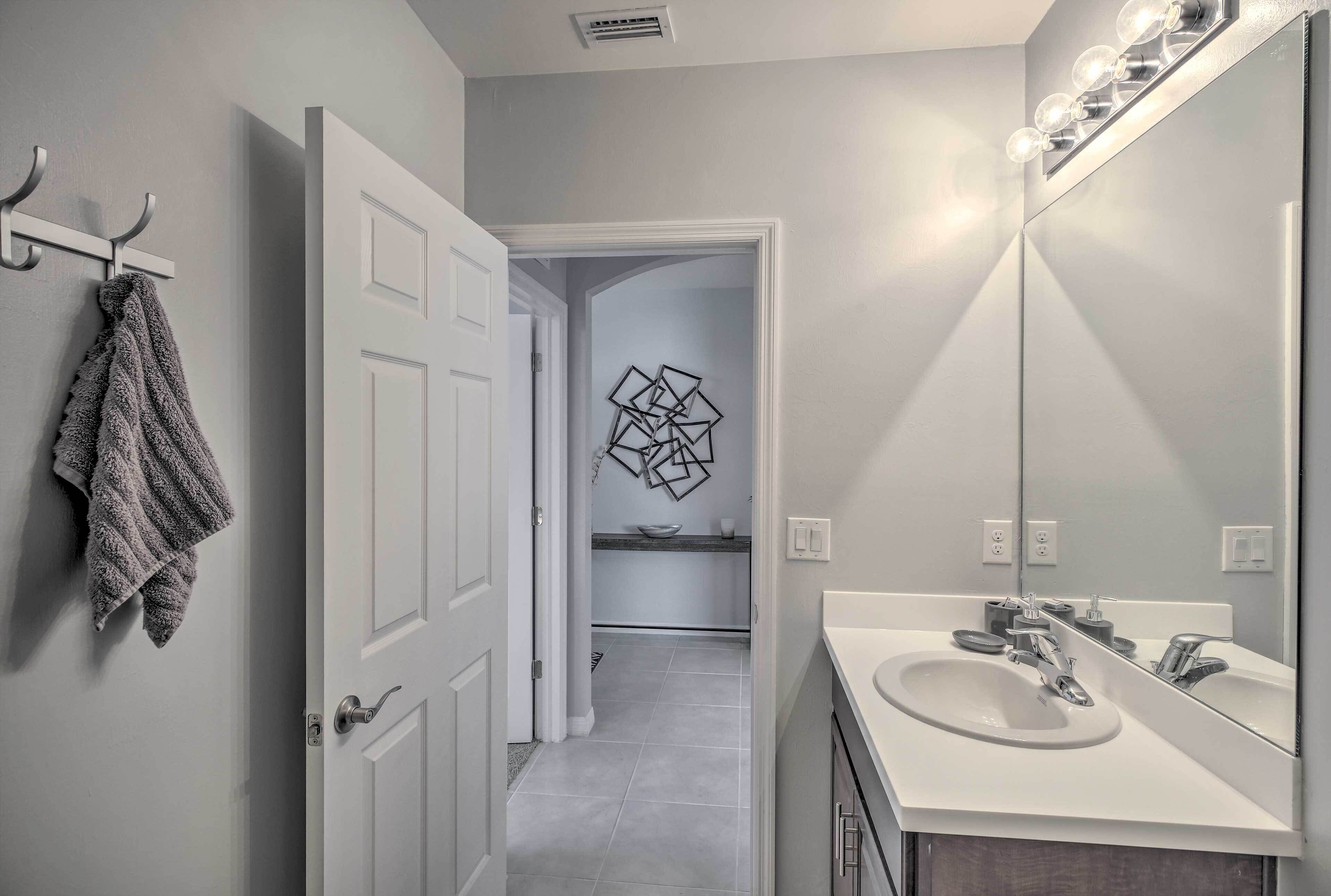 A bathroom with a white sink, a large mirror, and a towel rack.