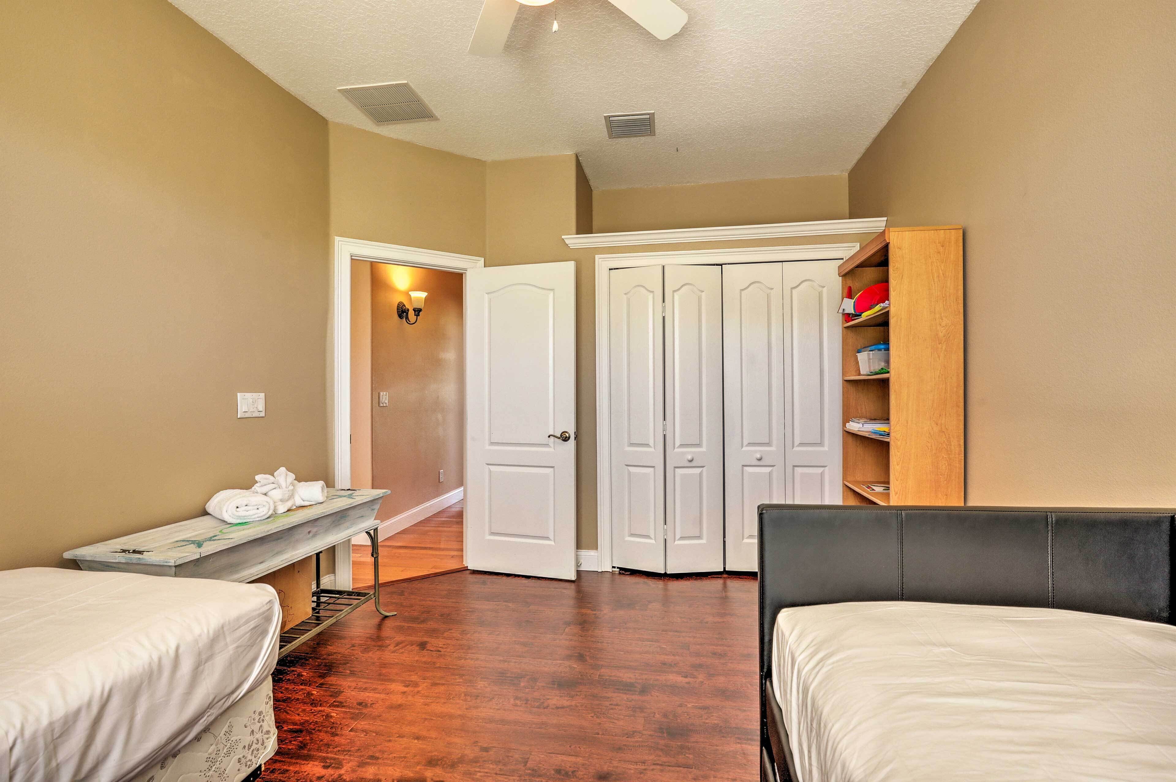 A bedroom with two beds, a bench, and a wardrobe.