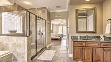 A spacious bathroom with a glass-enclosed shower, a large mirror, and a vanity with a sink.