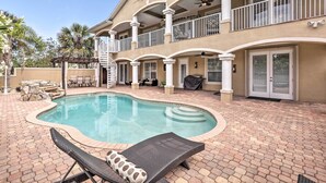 A two-story building with a swimming pool, outdoor seating, and a covered patio area.