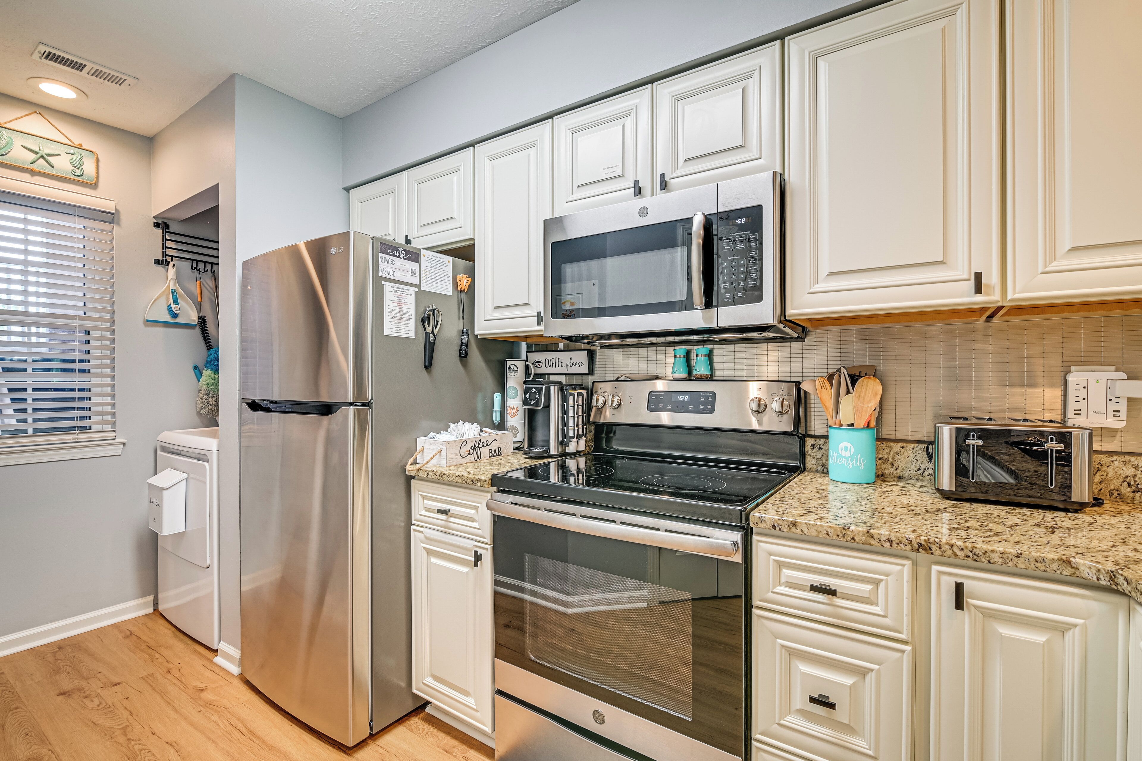 A modern kitchen with stainless steel appliances, white cabinetry, and a granite countertop.
