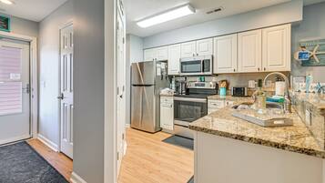 A modern kitchen with white cabinets, stainless steel appliances, and a granite countertop.