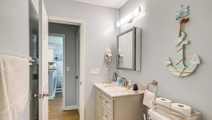 A bathroom with a sink, toilet, and a mirror. There is a towel rack and a wooden box with toilet paper. - 1st-floor Condo w/ Pool on Intracoastal Waterway! (Myrtle Beach)