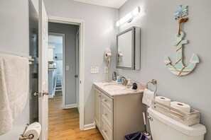 A bathroom with a sink, toilet, and a mirror. There is a towel rack and a wooden box with toilet paper. - 1st-floor Condo w/ Pool on Intracoastal Waterway! (Myrtle Beach)