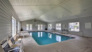 An indoor swimming pool with a tiled floor, benches along the sides, and a sign indicating pool rules.