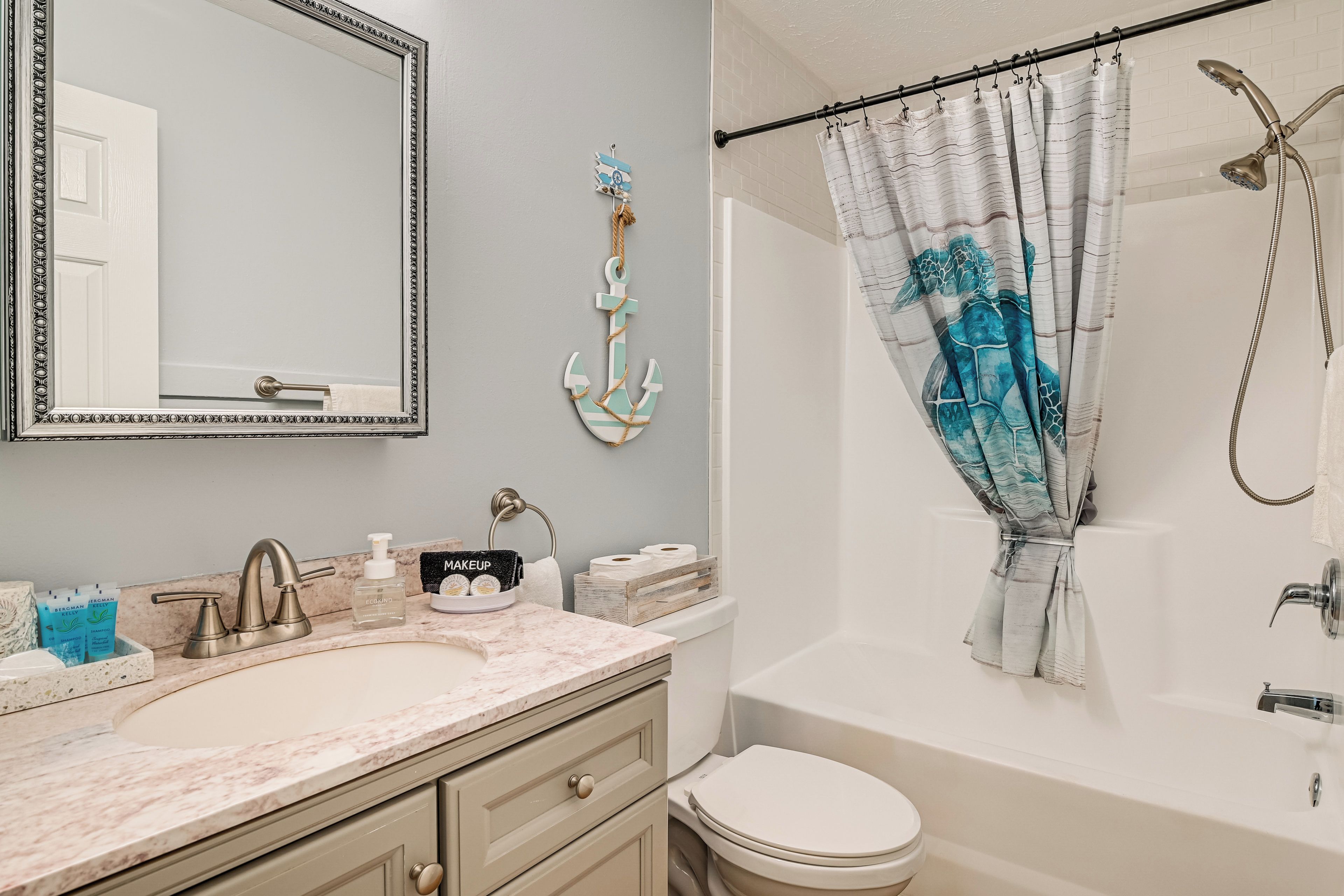 A bathroom with a sink, mirror, toilet, and shower.