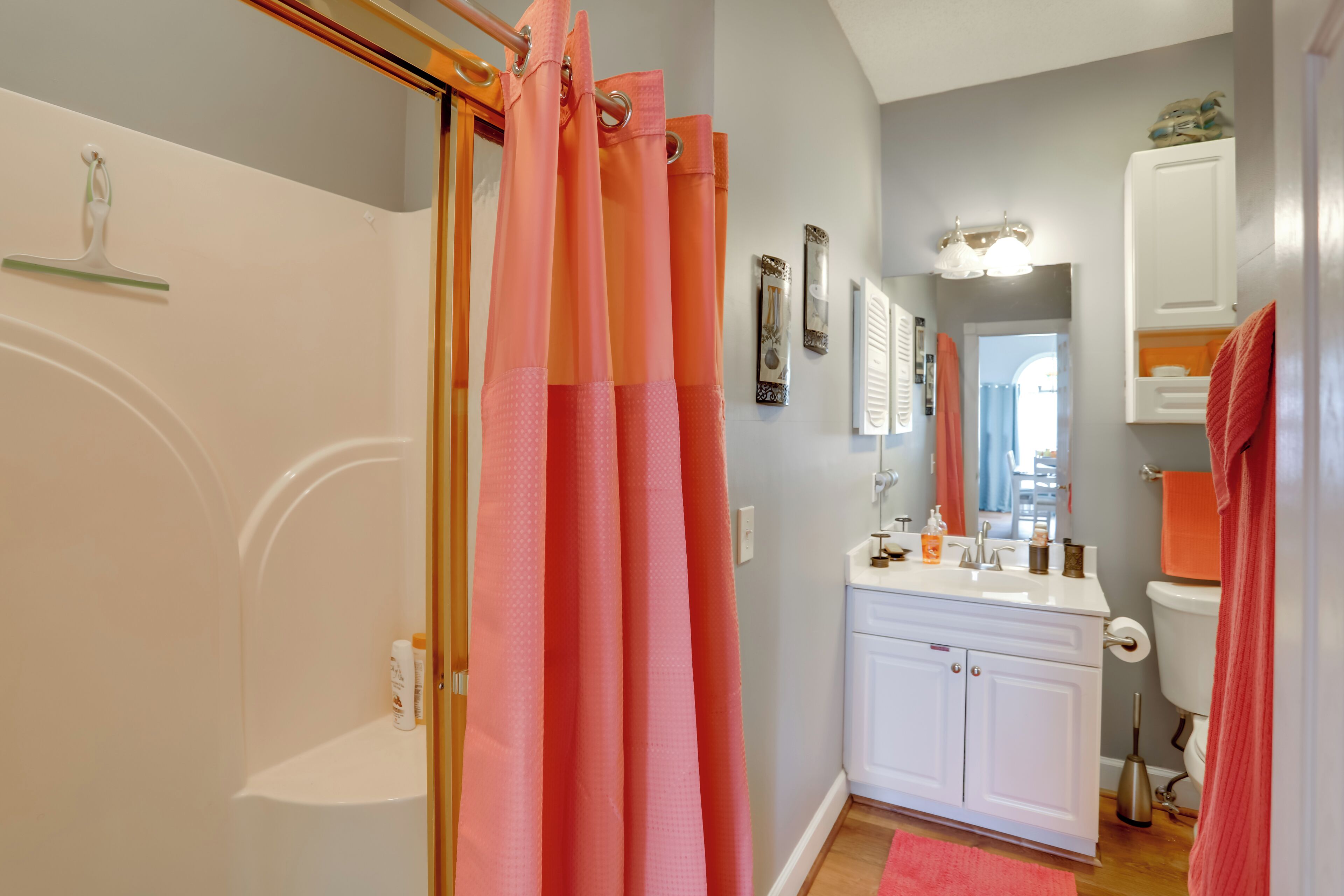 Une salle de bain avec un rideau de douche, un lavabo, un miroir et des toilettes.