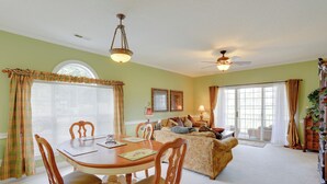 A dining area with a wooden table and chairs, a sofa in the background, and a ceiling fan. - 2 Mi to Broadway at the Beach: Myrtle Beach Condo (Myrtle Beach)