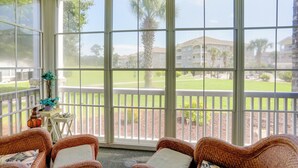 A sunroom with wicker furniture, large windows, and a view of a lawn and building. - 2 Mi to Broadway at the Beach: Myrtle Beach Condo (Myrtle Beach)