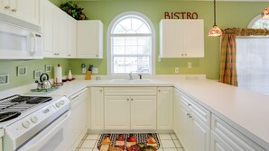 A kitchen with white cabinets, a stove, and a window with a 'BISTRO' sign. - 2 Mi to Broadway at the Beach: Myrtle Beach Condo (Myrtle Beach)