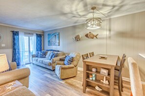 Ein gemütliches Wohnzimmer mit einer Couch, Sesseln, einem Esstisch und einer Deckenleuchte.