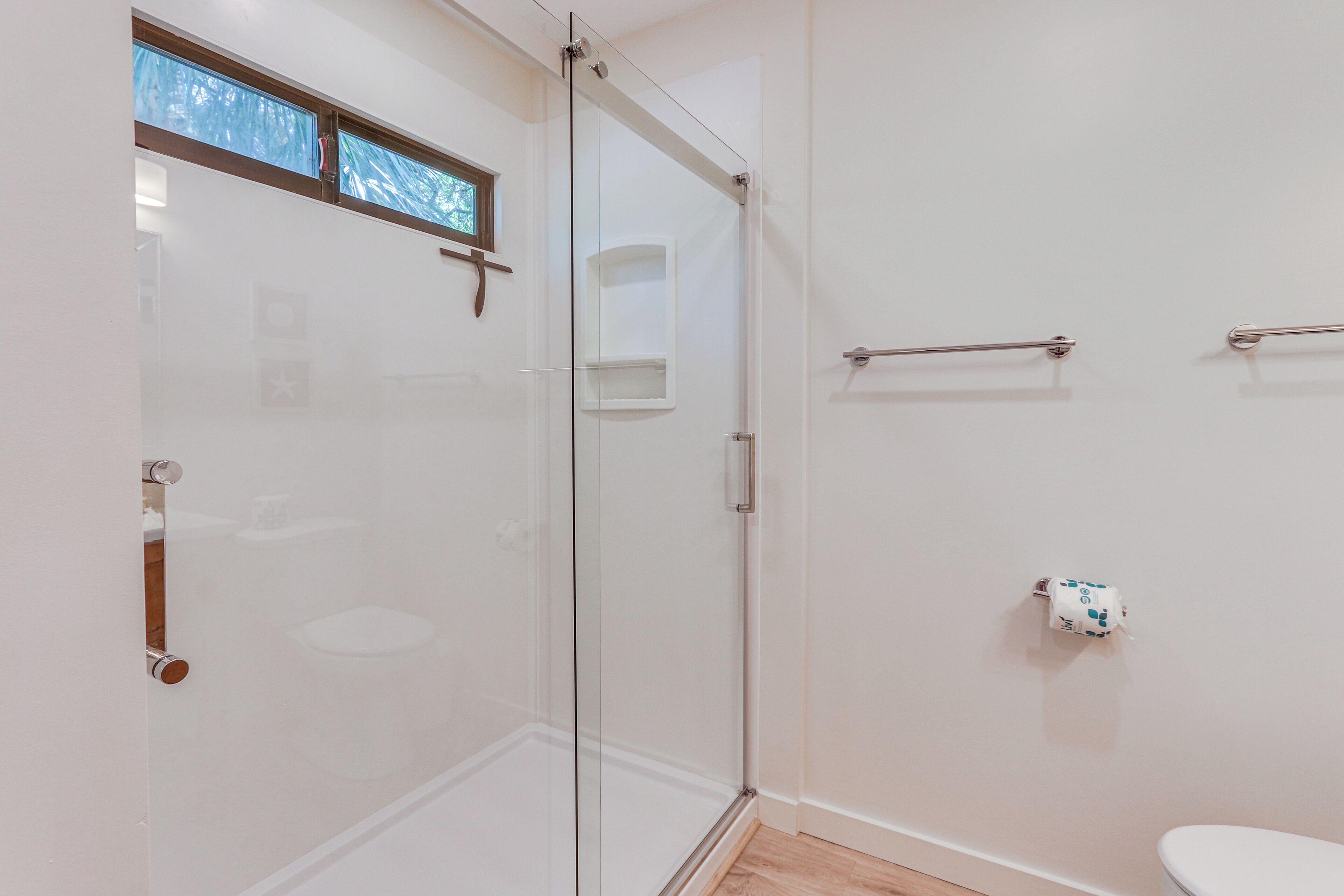 A modern bathroom with a glass shower enclosure, a toilet, and a towel rack.