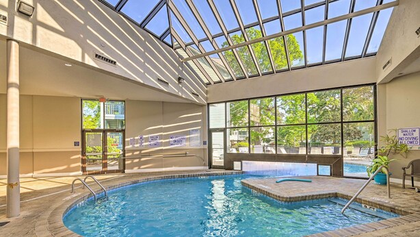Una piscina interior con techo de cristal, señalización clara y suelo de baldosas.