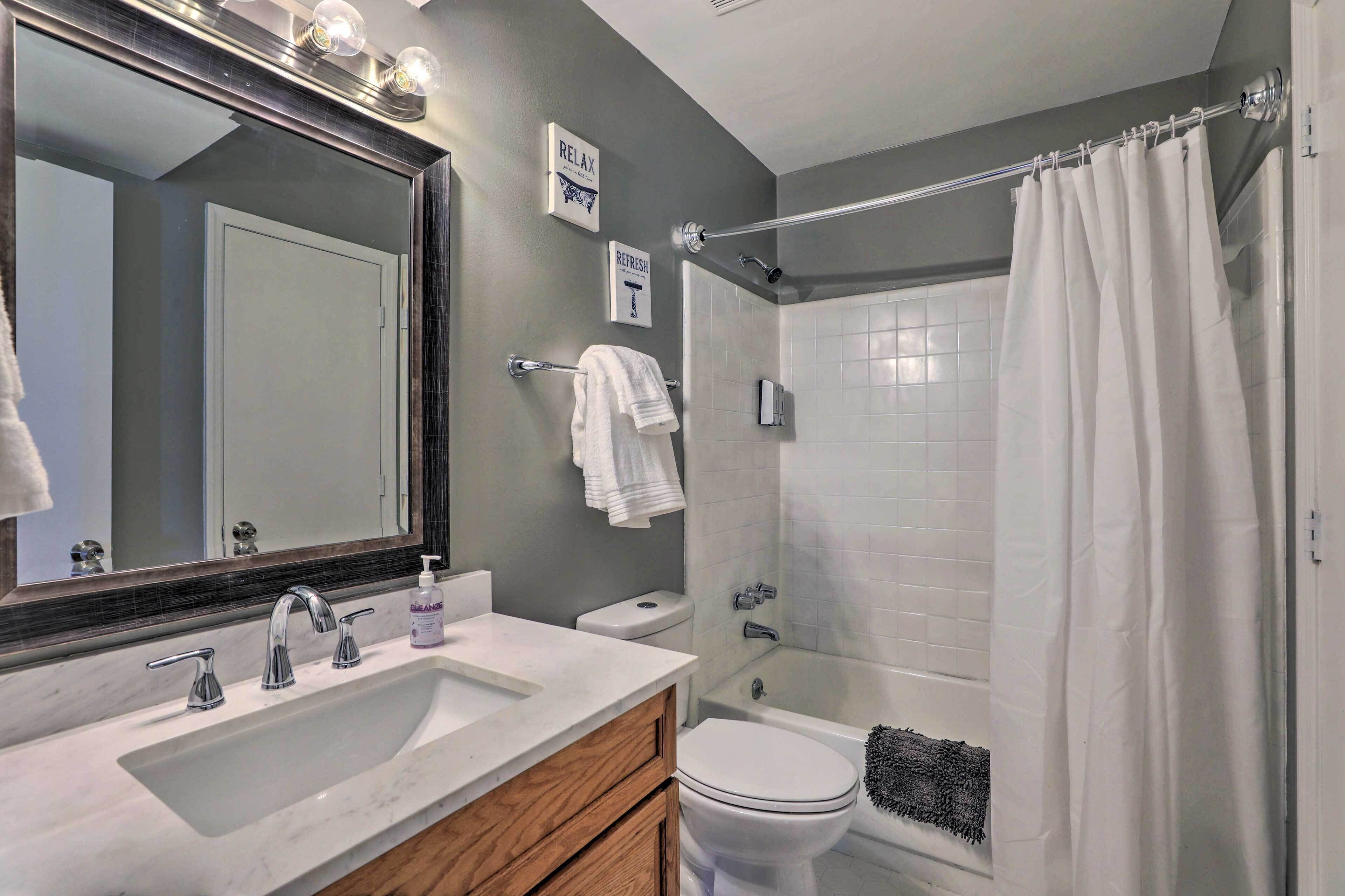 A modern bathroom with a large mirror, a sink, a toilet, and a shower.