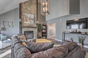 Un salon moderne avec une cheminée en pierre, un canapé en cuir et un téléviseur à écran plat.