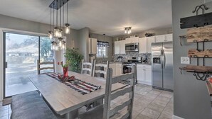 Une cuisine moderne avec des meubles blancs, des appareils en acier inoxydable et un coin repas comprenant une table et des chaises en bois.
