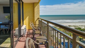 Ein Balkon mit Blick auf den Strand, einem Tisch mit Stühlen und einem Blumentopf.