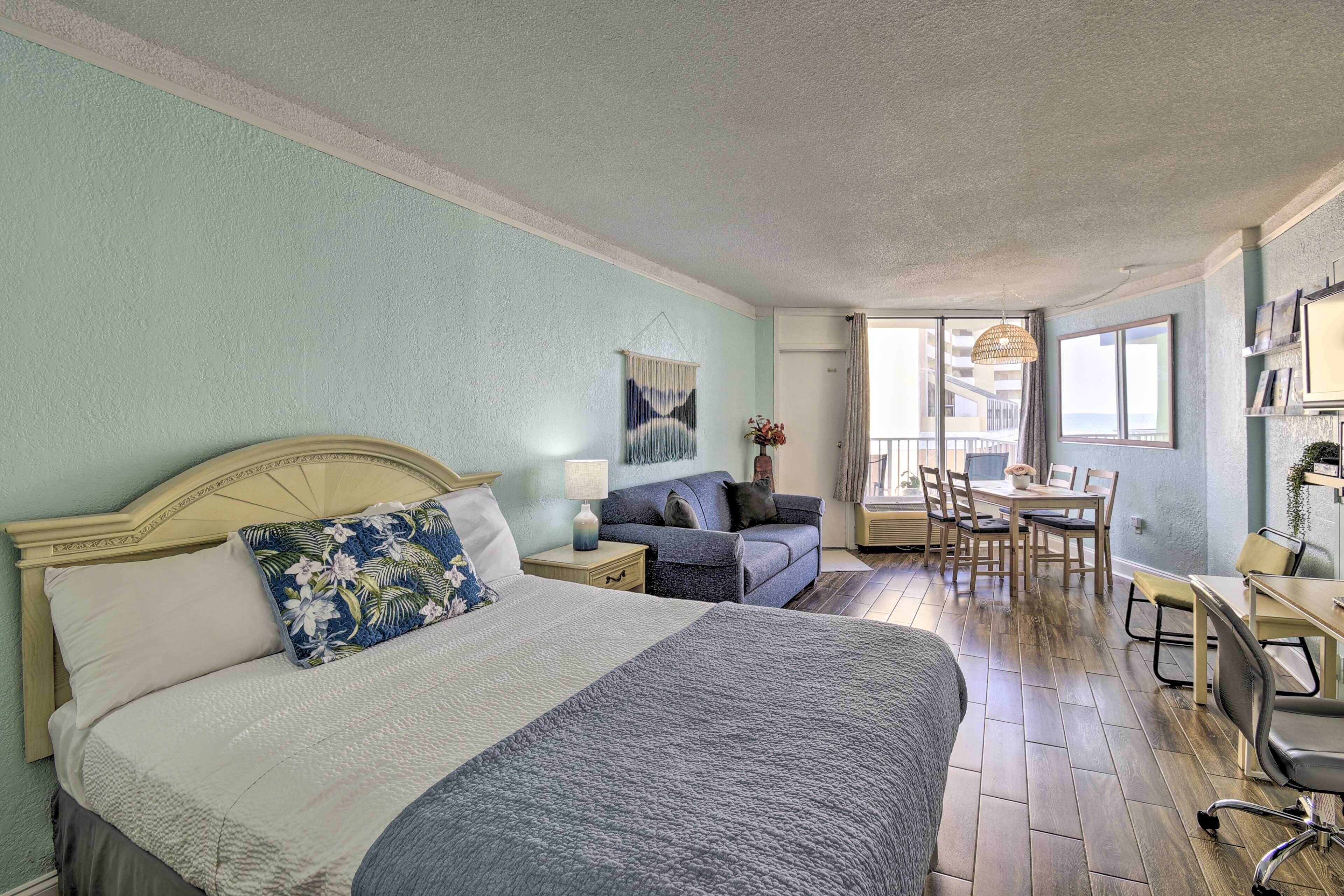 Une chambre avec un grand lit, un canapé, une table à manger et un balcon avec vue.