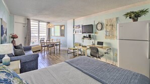 Ein modernes Zimmer mit Bett, Schreibtisch, Stuhl, Fernseher und Kühlschrank.
