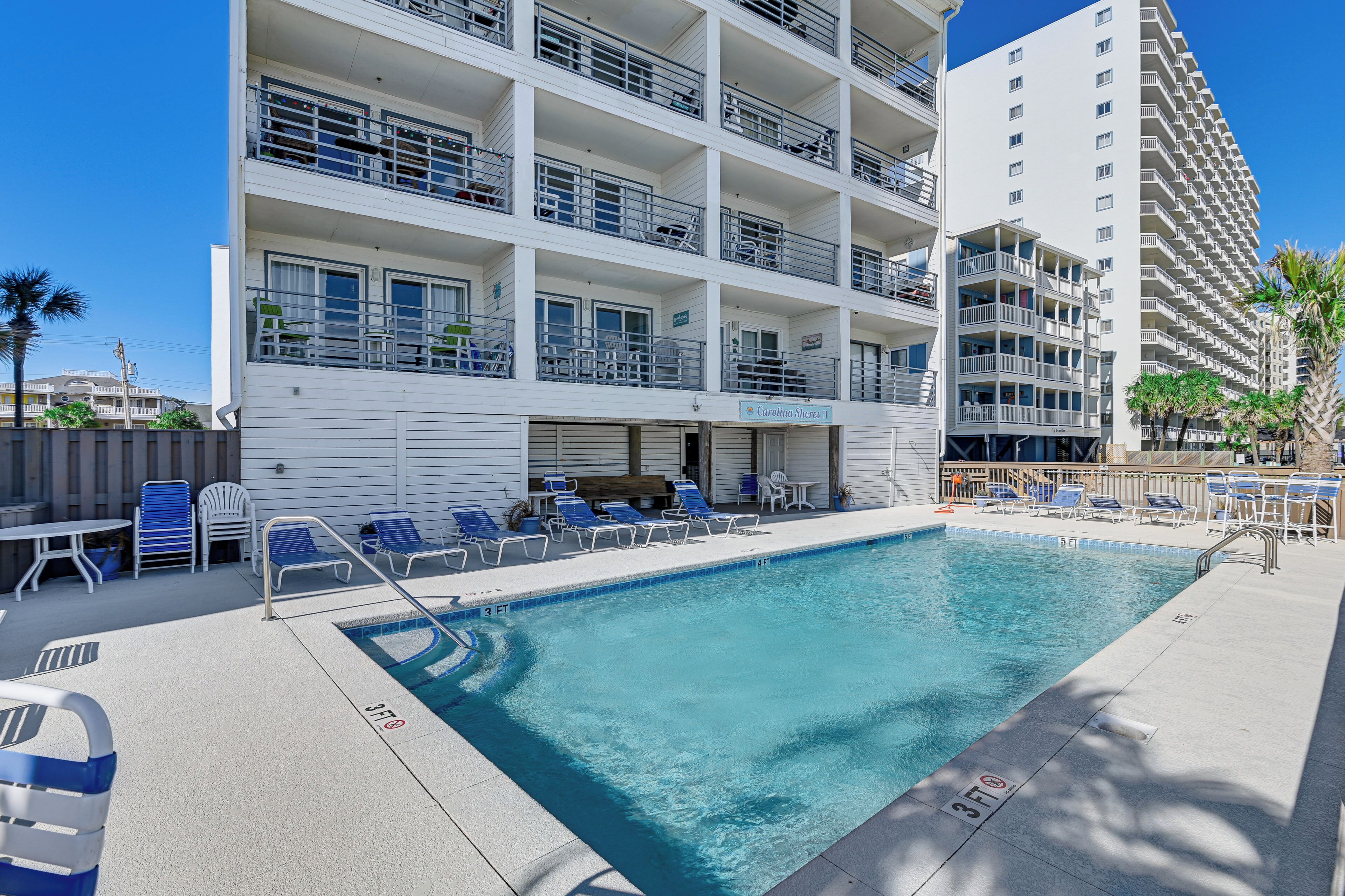 A pool area with lounge chairs and a sign for 'Carolina Shore'.