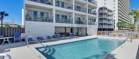 A pool area with lounge chairs and a sign for 'Carolina Shore'.