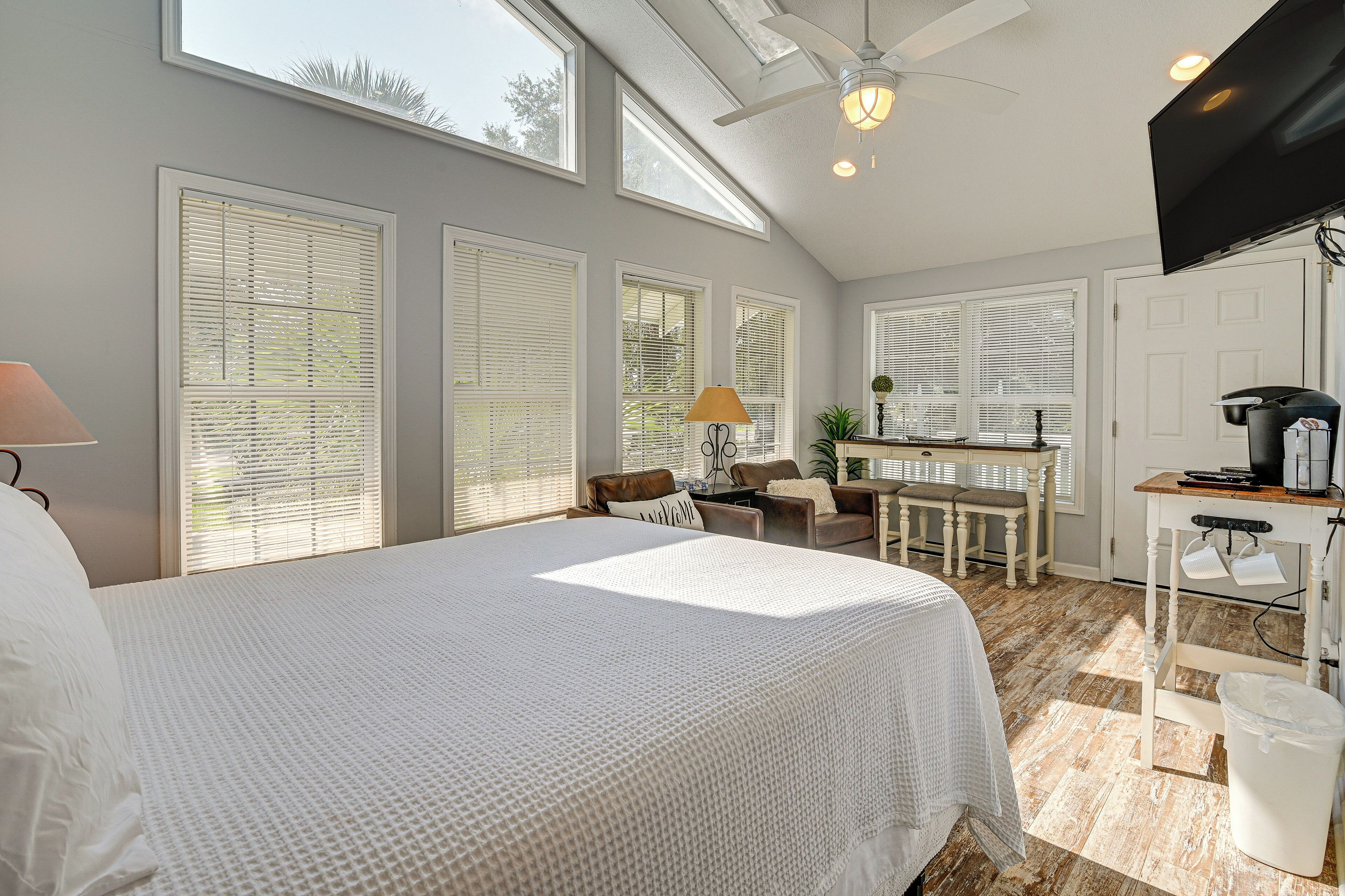 A bedroom with a large bed, a desk, and a television.