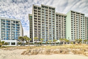 A beachfront hotel with multiple high-rise buildings, balconies, and palm trees. - Oceanfront Myrtle Beach Rental w/ Pool! (Myrtle Beach)