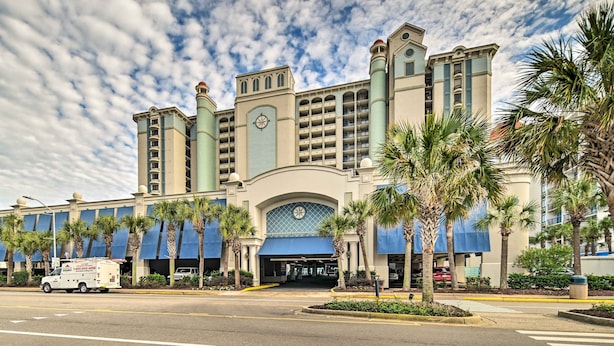 A hotel with a large entrance, palm trees, and a parking lot. - Oceanfront Myrtle Beach Rental w/ Pool! (Myrtle Beach)