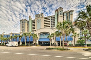 A hotel with a large entrance, palm trees, and a parking lot. - Oceanfront Myrtle Beach Rental w/ Pool! (Myrtle Beach)