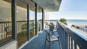 A balcony with chairs and a table, overlooking a beach. - Oceanfront Myrtle Beach Rental w/ Pool! (Myrtle Beach)
