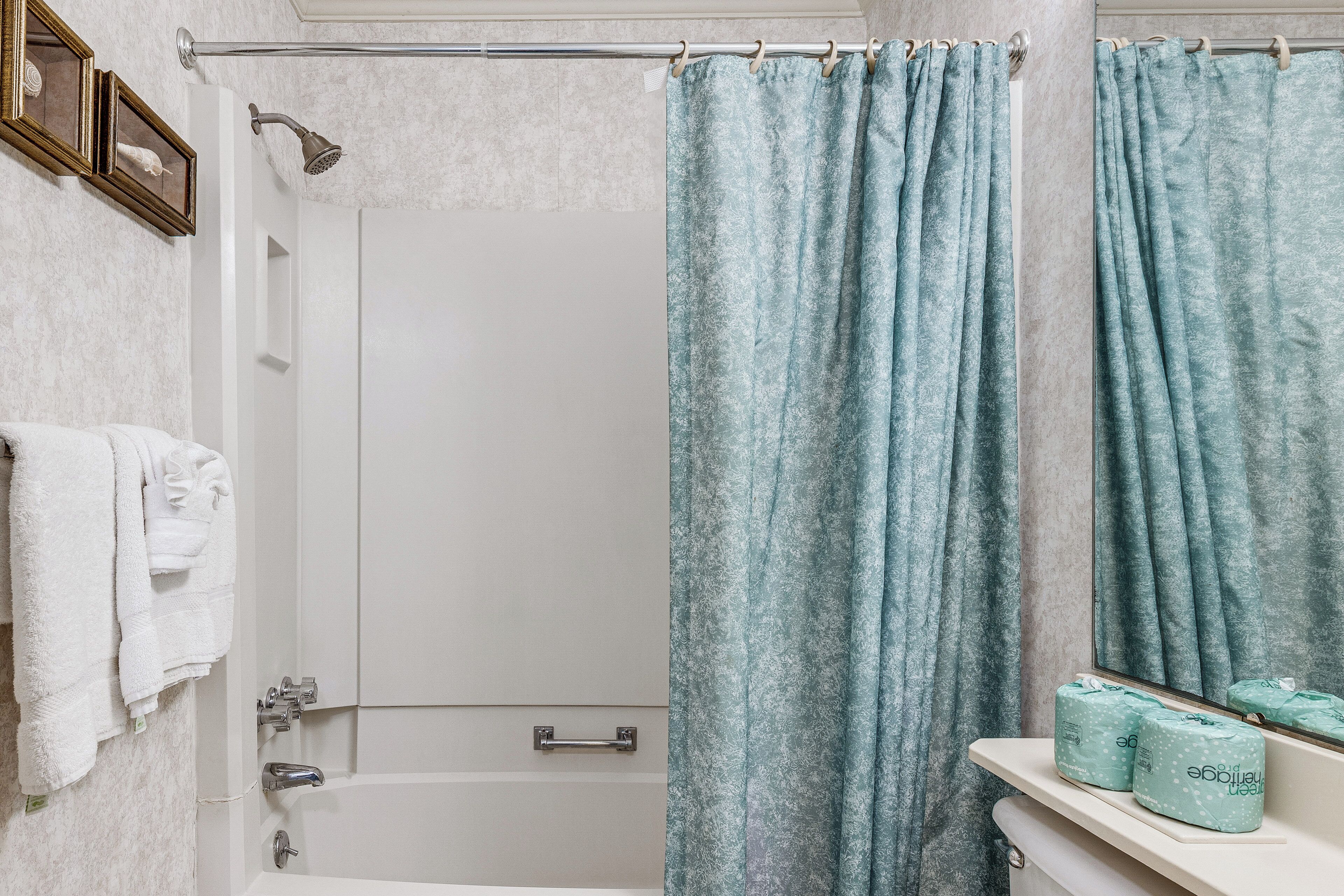 Un bagno con tenda della doccia, una vasca, il water e un portasciugamani.