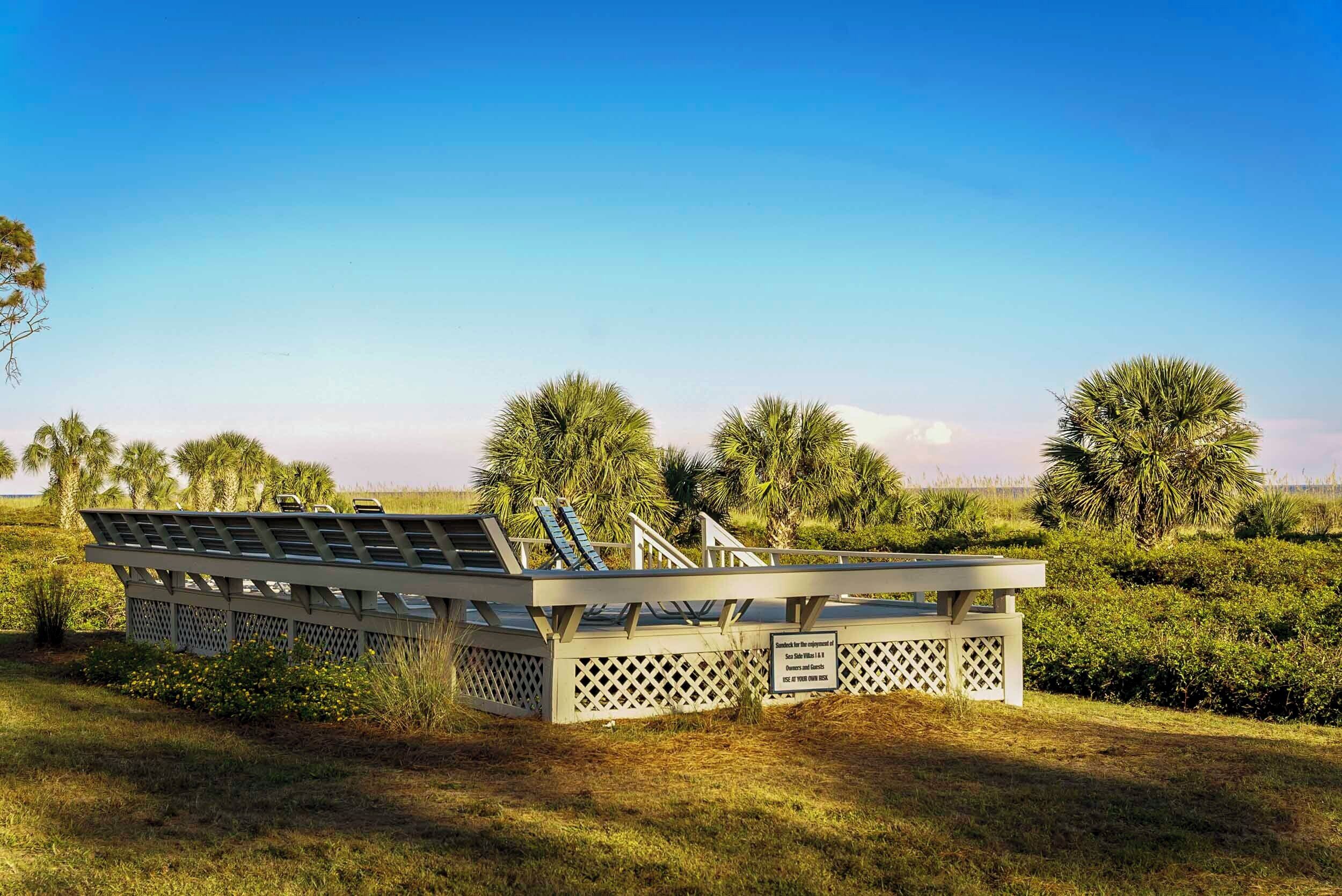Une grande structure en forme de navire, dotée d’un pont et de rambardes, entourée d’herbe et d’arbres.