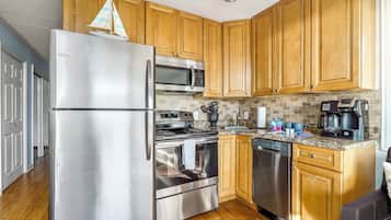 Una cocina moderna con electrodomésticos de acero inoxidable, armarios de madera y salpicadero de azulejos.