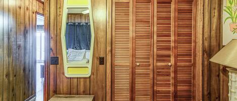 A wooden interior with a wooden door, a small wooden cabinet, and a wall-mounted mirror.