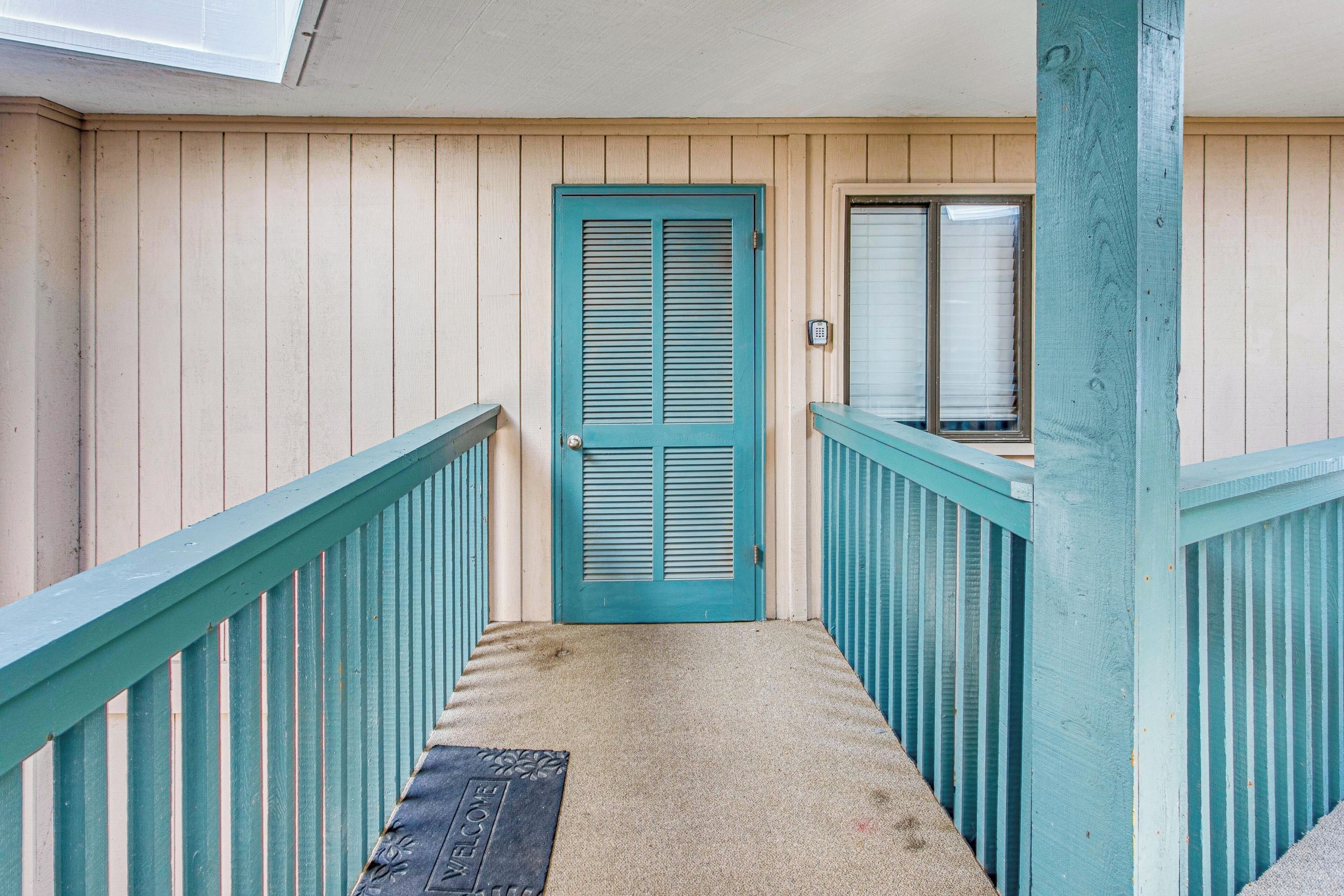 A wooden exterior with a teal door and a small porch area.