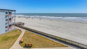 A beachfront hotel with a balcony, a sandy beach, and a wooden fence. - ~ 9 Mi to Boardwalk: Oceanfront Myrtle Beach Condo (Myrtle Beach)