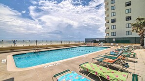 A swimming pool with lounge chairs and a view of the ocean. - Oceanfront Myrtle Beach Condo w/ Outdoor Pool (Myrtle Beach)