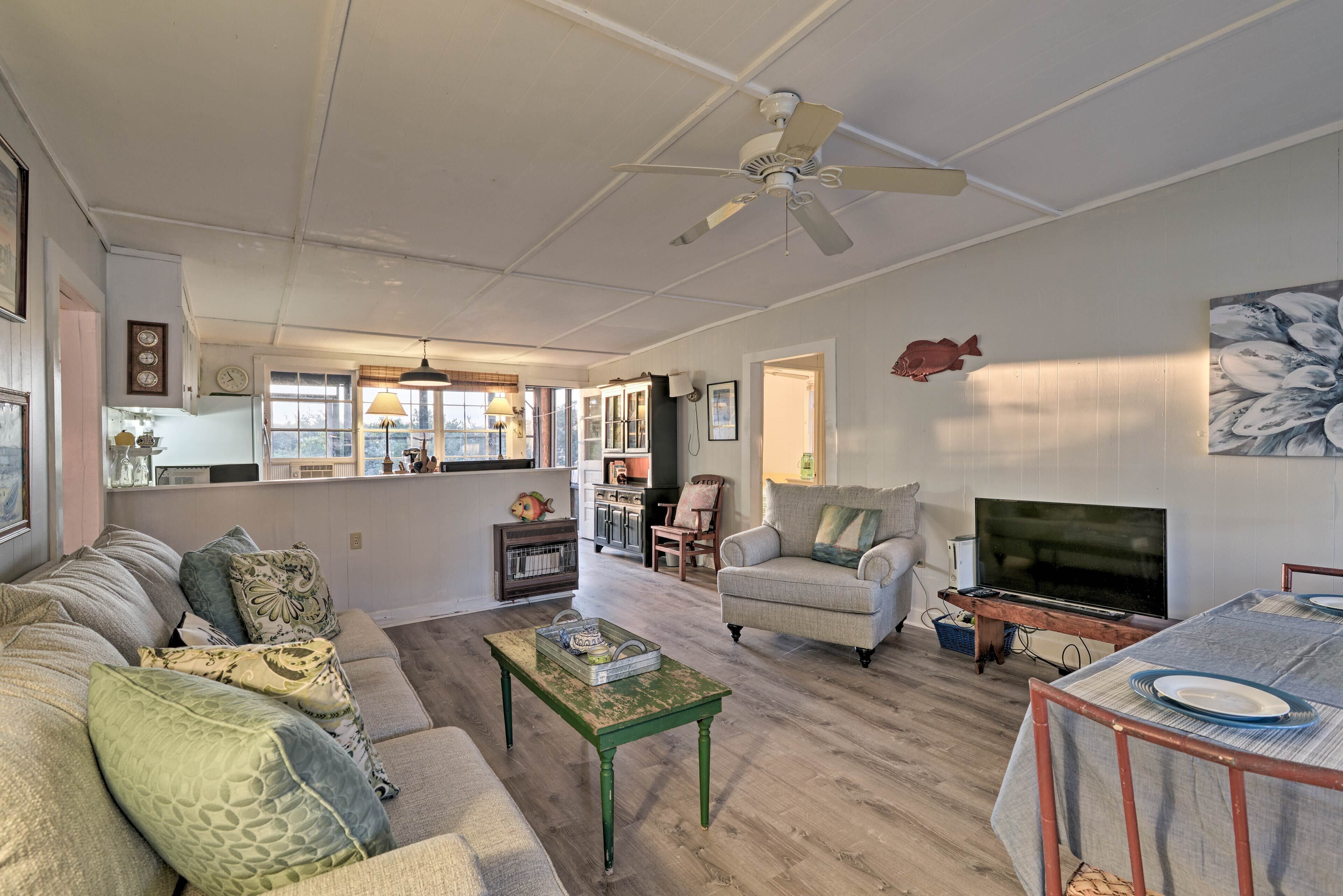 A spacious living room with a green coffee table, a beige sofa, and a television on a wooden stand.