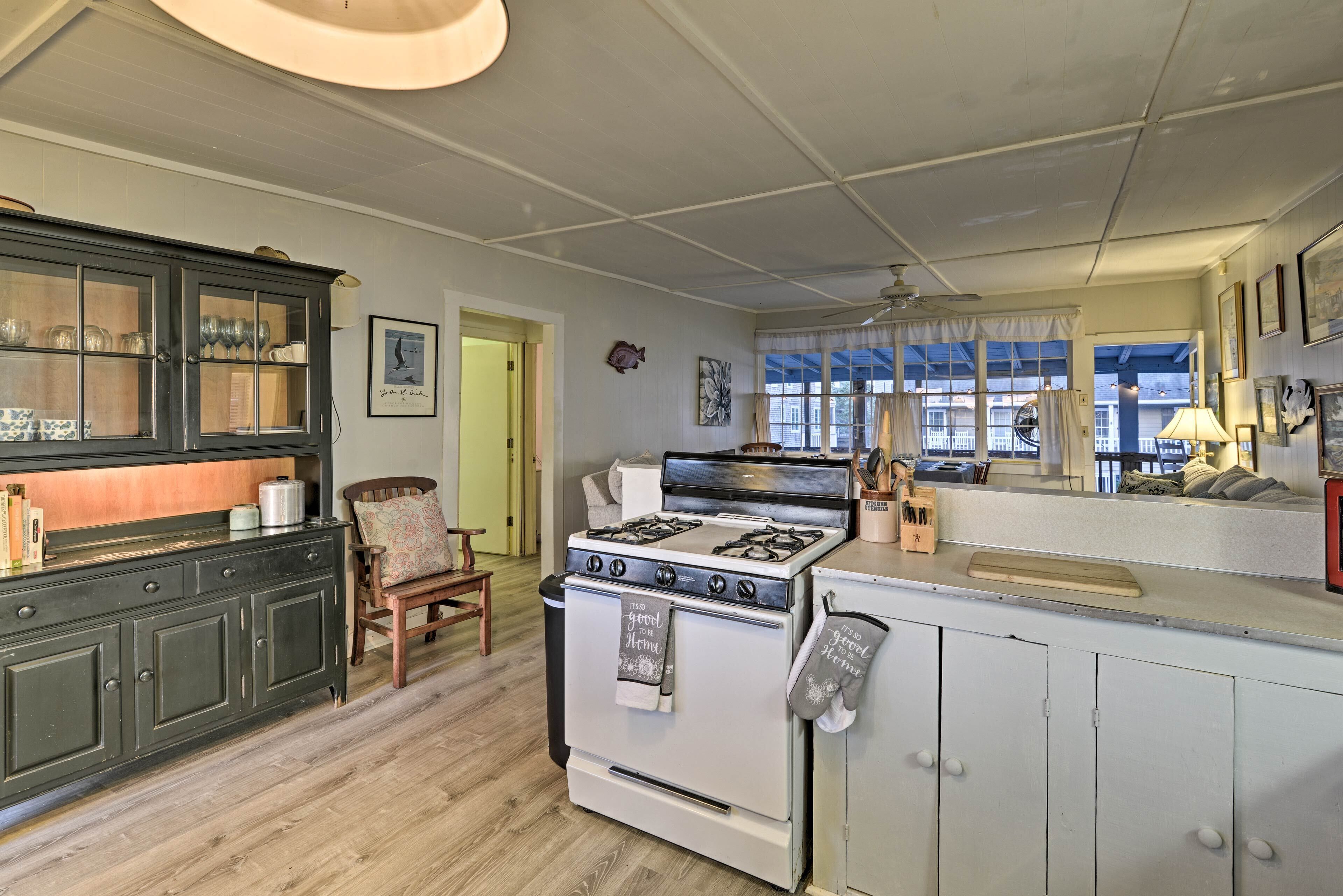 A kitchen with a stove, cabinets, and a window with a view.
