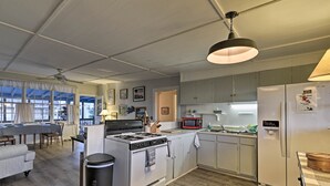 A spacious kitchen with a stove, microwave, and refrigerator, wooden flooring, and a dining area with a table and chairs. - Pawleys Island House, - Steps to Beach & Creek! (Pawleys Island)