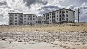 A multi-story building with balconies, situated on a sandy slope. - Oceanfront Ormond Beach Condo w/ Pool Access! (Ormond Beach)