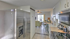 A modern kitchen with stainless steel appliances, a dining area with a table and chairs, and a ceiling fan. - Oceanfront Ormond Beach Condo w/ Pool Access! (Ormond Beach)