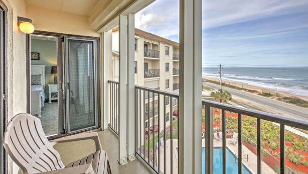 A balcony with a chair, a sliding glass door, and a view of the ocean and beach. - Oceanfront Ormond Beach Condo w/ Pool Access! (Ormond Beach)