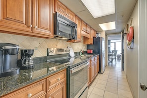 A modern kitchen with wooden cabinets, stainless steel appliances, and a tiled backsplash. - Oceanfront Balcony: Resort Condo in Myrtle Beach (Myrtle Beach)